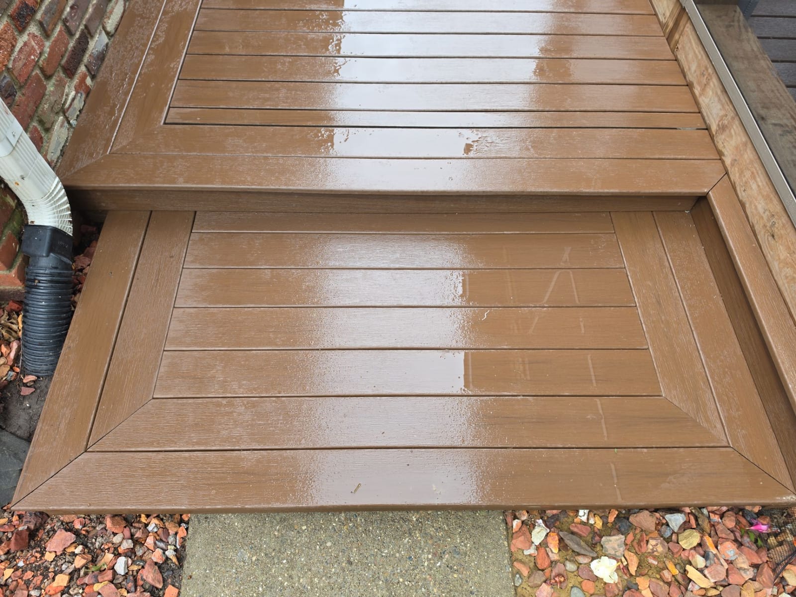 Composite deck step and landing with a double picture-frame border, wet after rain