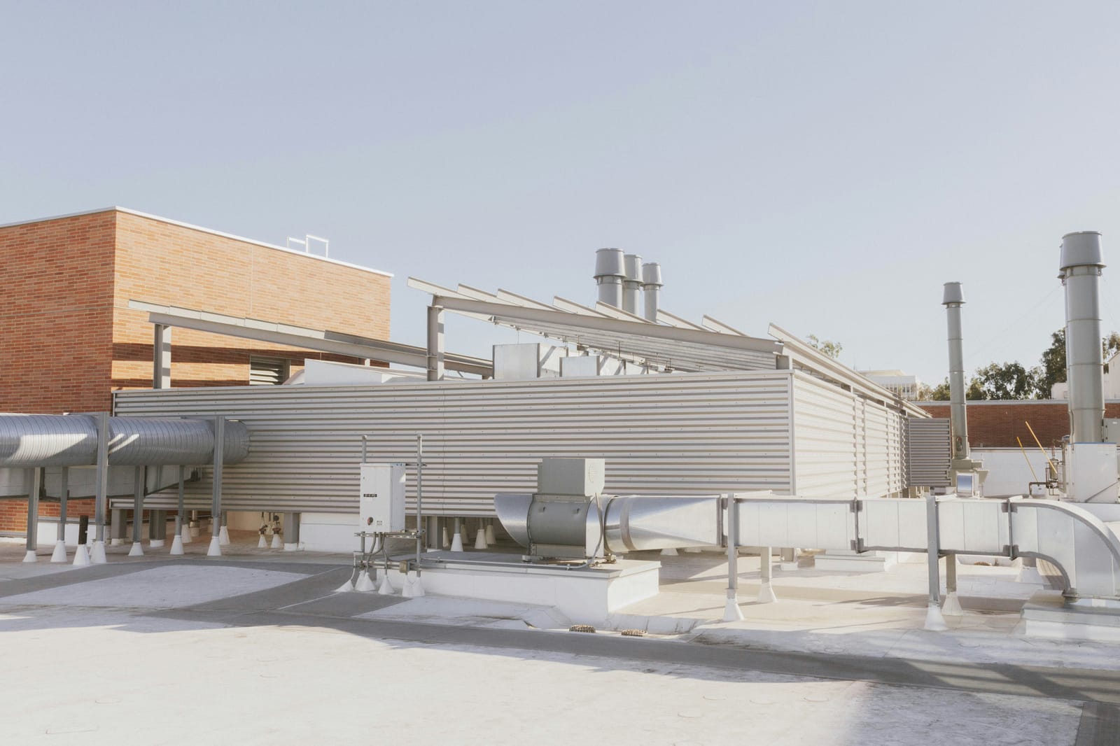 Example of white membrane flat roof with ductwork, an exhaust fan on a curb and mechanical screens on a commercial building (stock photo)