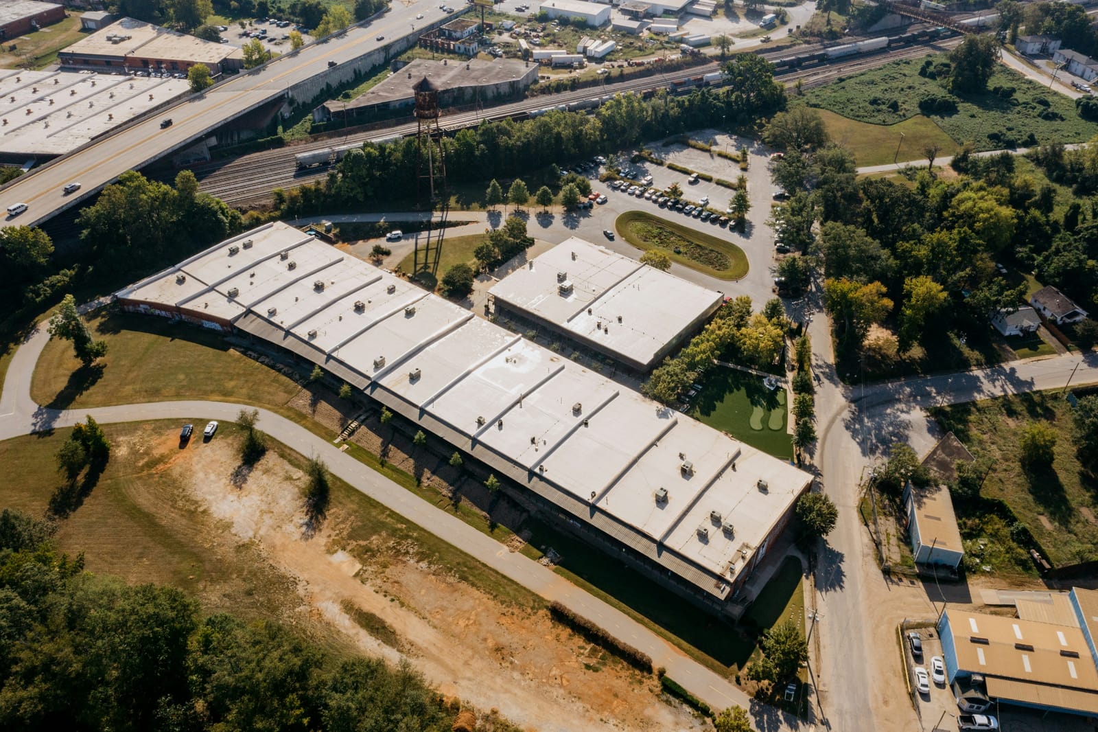 Example of aerial view of a long commercial building and a second building with white flat roofs and rooftop HVAC units (stock photo)