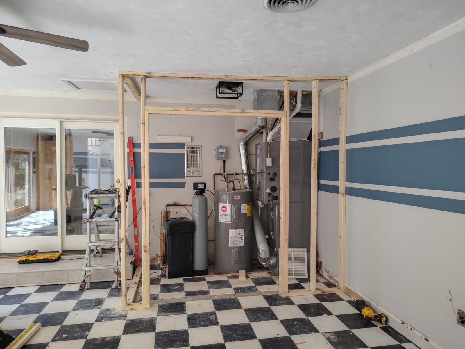 Fresh 2x4 stud framing for a closet around a furnace, water heater and softener on a checkered floor