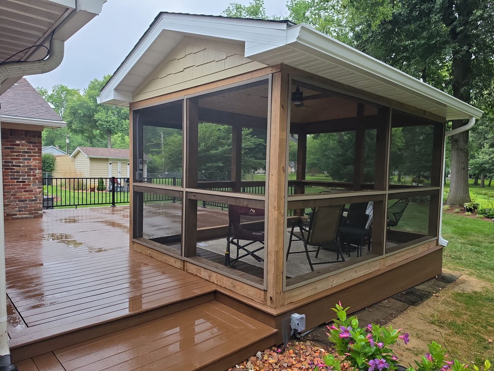Screened porch with wood posts, shake-siding gable and white gutters, built onto a brown composite deck