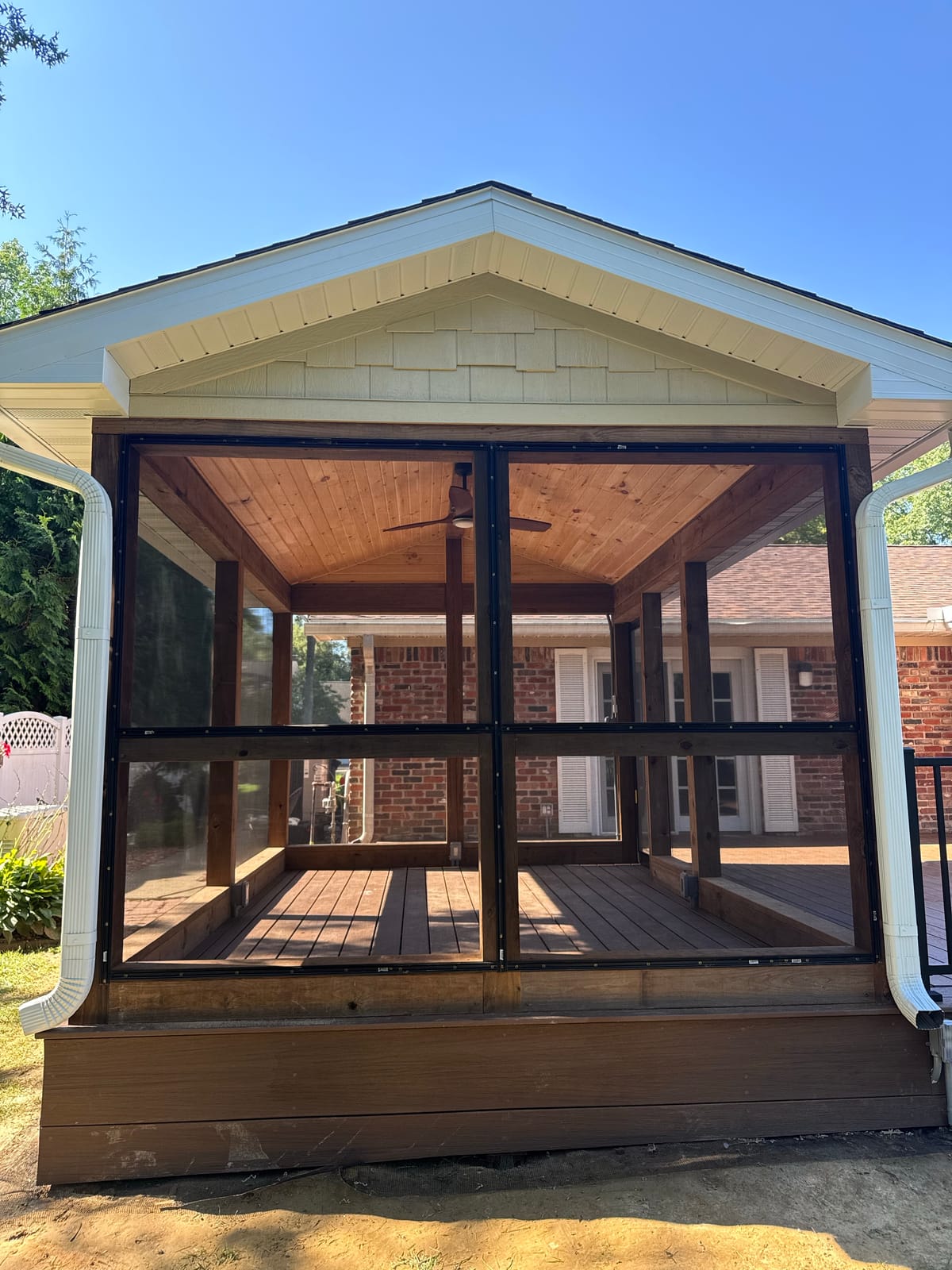 Screened porch with knotty pine ceiling, fan, cedar-tone posts and shake gable on a brown composite deck